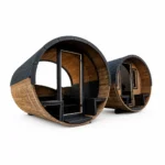 Sauna extérieur 5 Sauna tonneau TimberIN Nordic Barrel Panorama, avec coque arrondie en bardeaux foncés et façade panoramique incurvée entièrement vitrée sur fond blanc