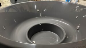 Éclairage sous-marin LED dans un bain nordique, avec raccord d'évacuation visible, avec cuve intérieure moulé gris foncé