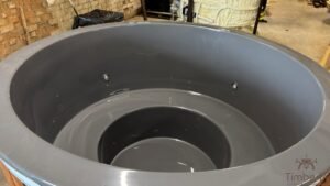 Vue rapprochée de l'intérieur vide en PRV gris d'un bain nordique, avec une banquette circulaire moulée, un espace central profond pour les pieds