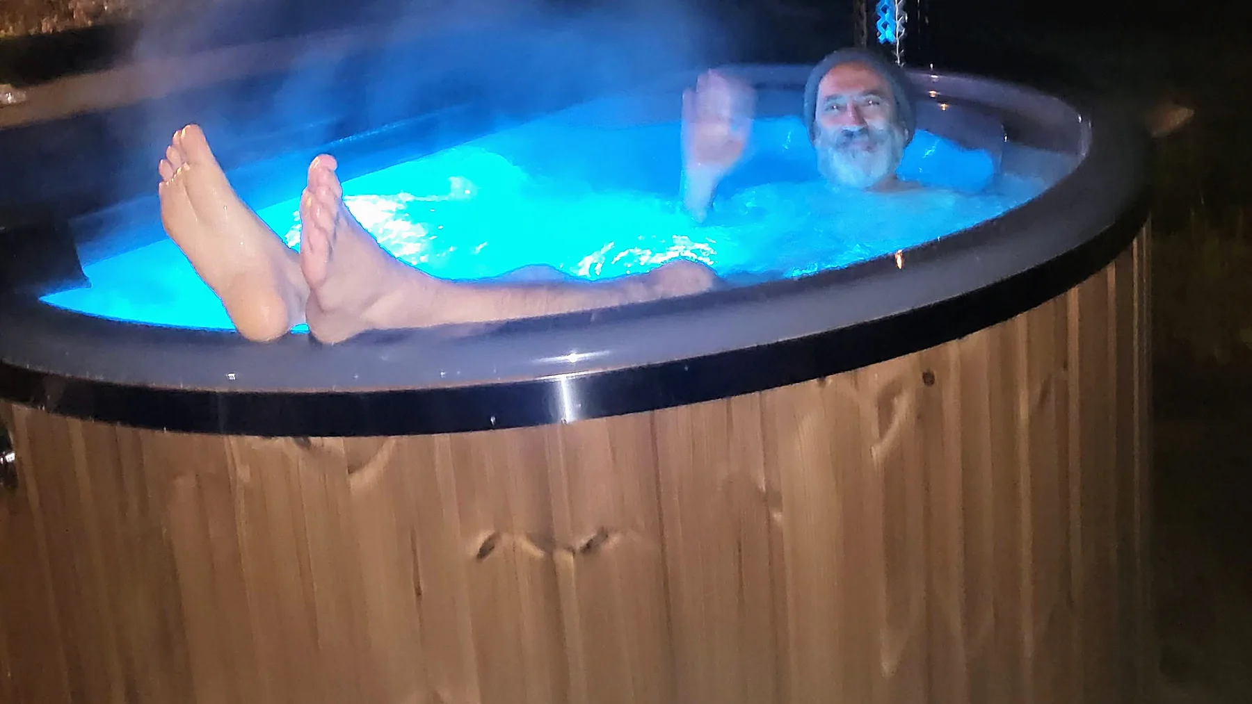 Baigneurs dans un bain nordique TimberIN éclairé le soir