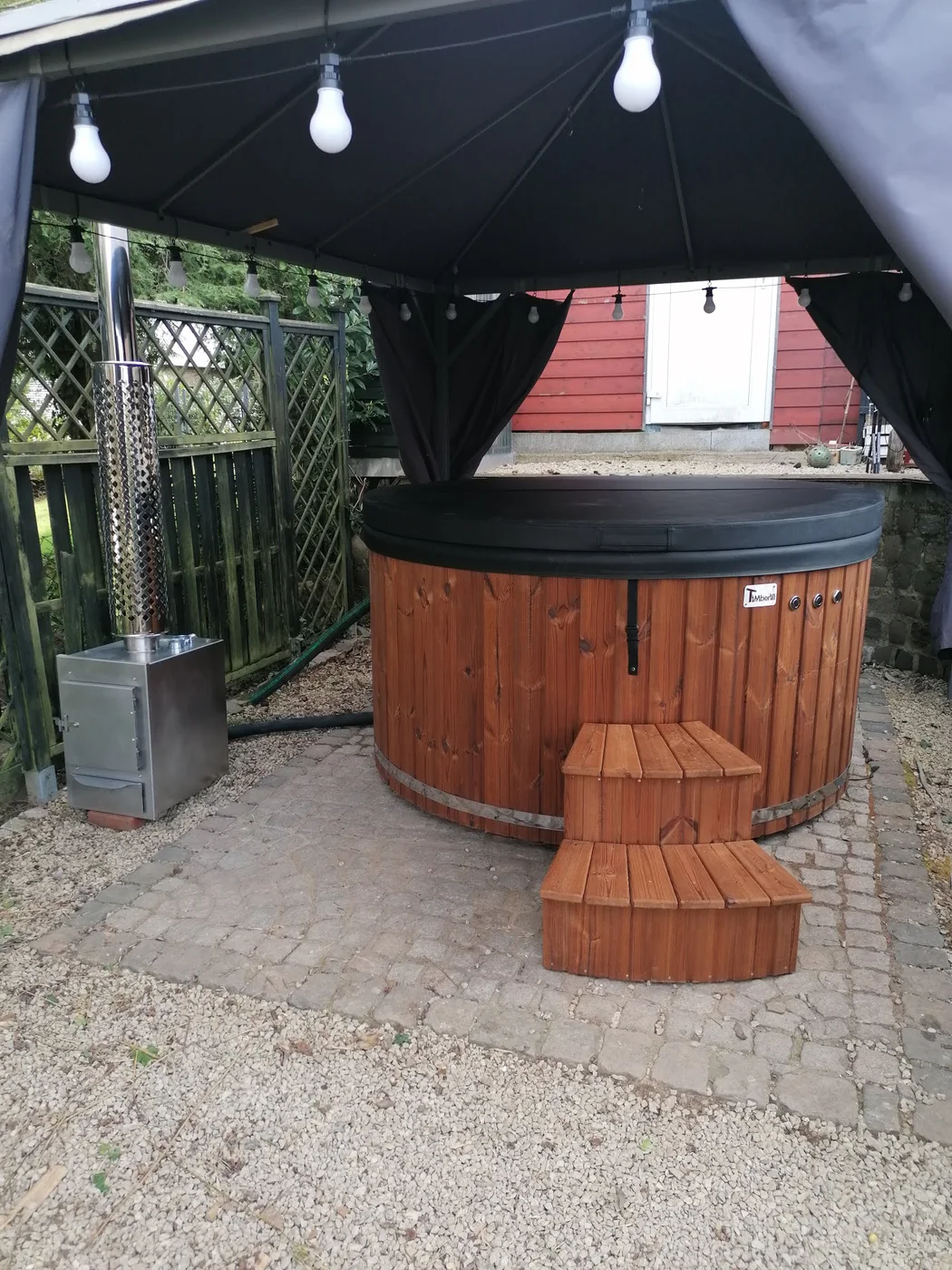 Bain nordique TimberIN éclairé sous une pergola