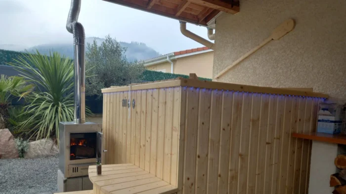 Poêle extérieur allumé à côté d’un bain nordique TimberIN en bois