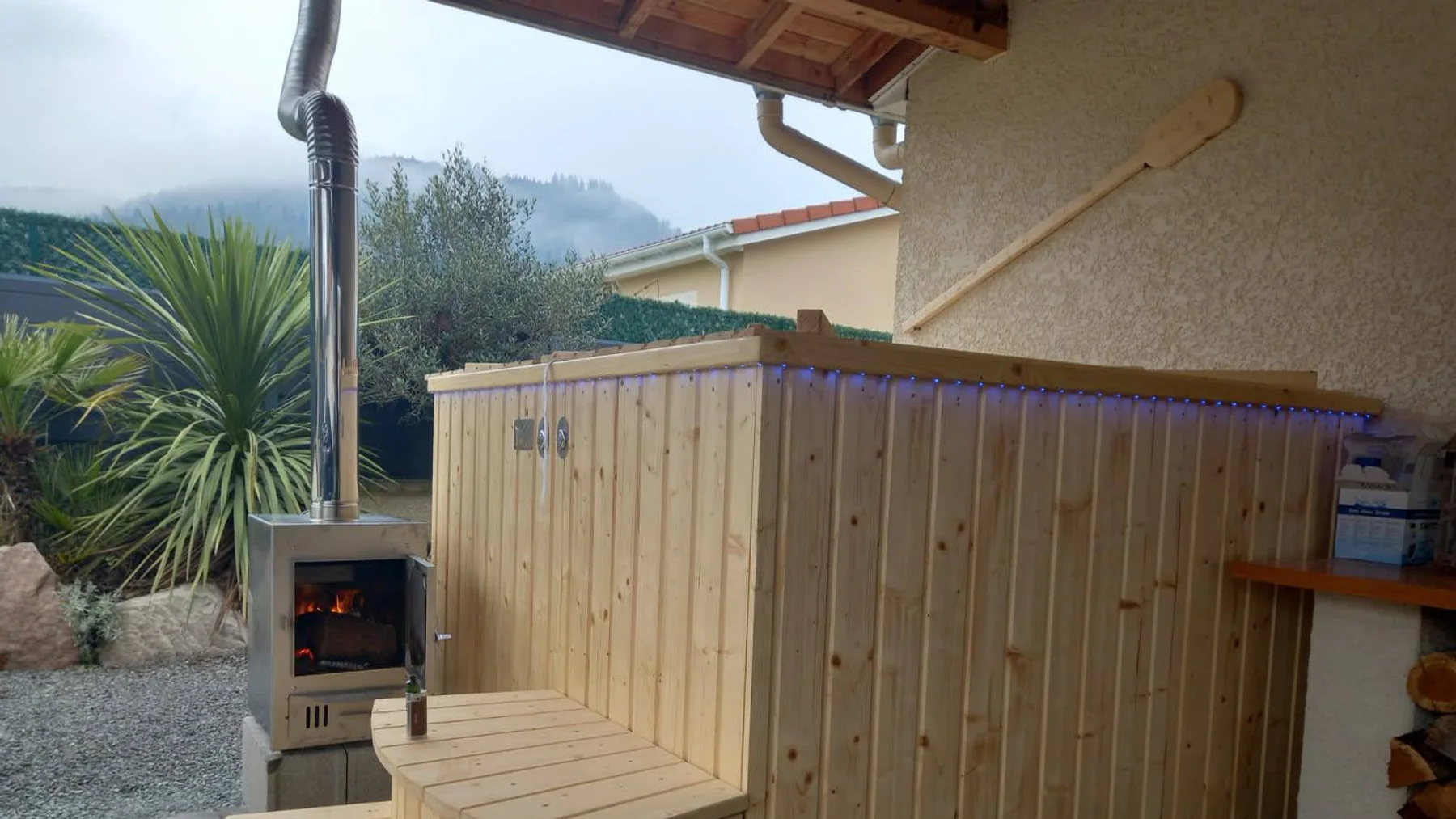 Poêle extérieur allumé à côté d’un bain nordique TimberIN en bois