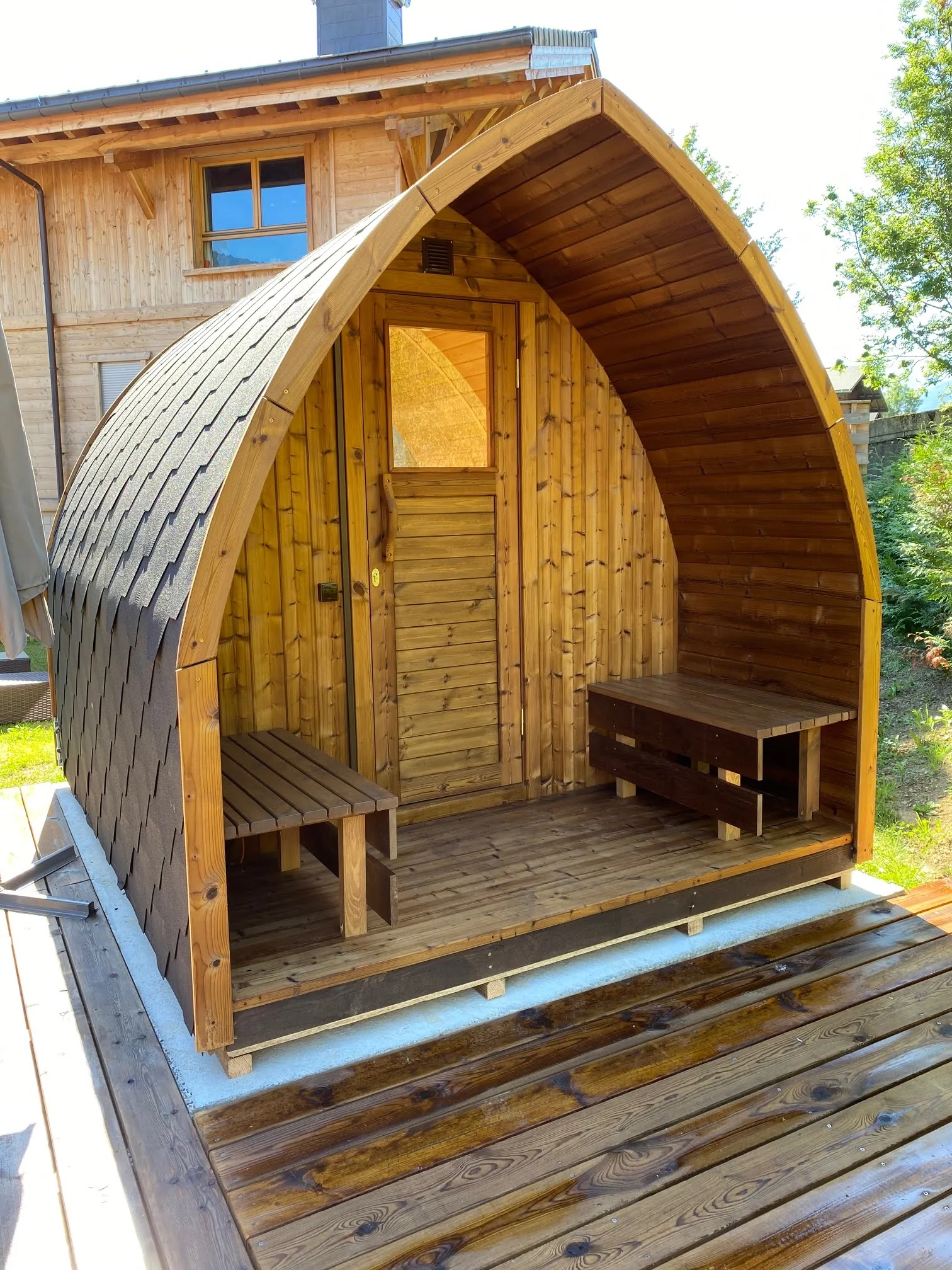 Pourquoi choisir TimberIN ? 7 Sauna pod en bois avec porche couvert et bancs extérieurs installé sur une terrasse