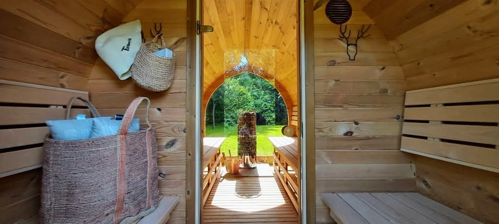 Intérieur de sauna avec bancs en bois et porte vitrée donnant sur le jardin