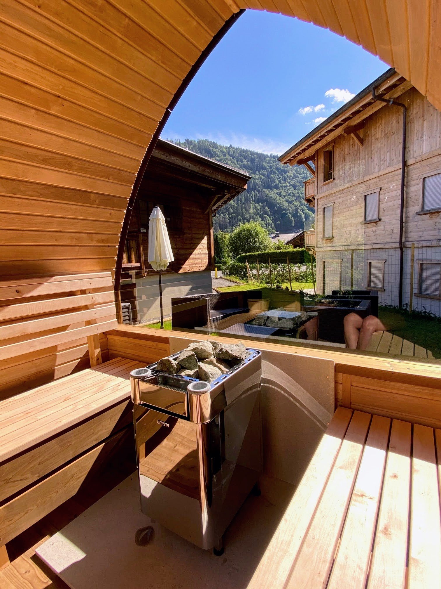 Sauna extérieur 2 personnes 1 Deux bancs en bois et un poêle dans un sauna à façade vitrée